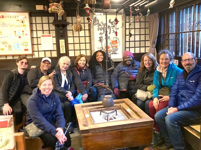       Group of people seated inside a traditional Japanese house with smiles.
  