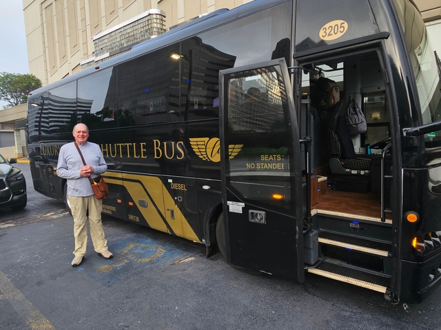       A person standing next to a luxury shuttle bus in a city environment.
  