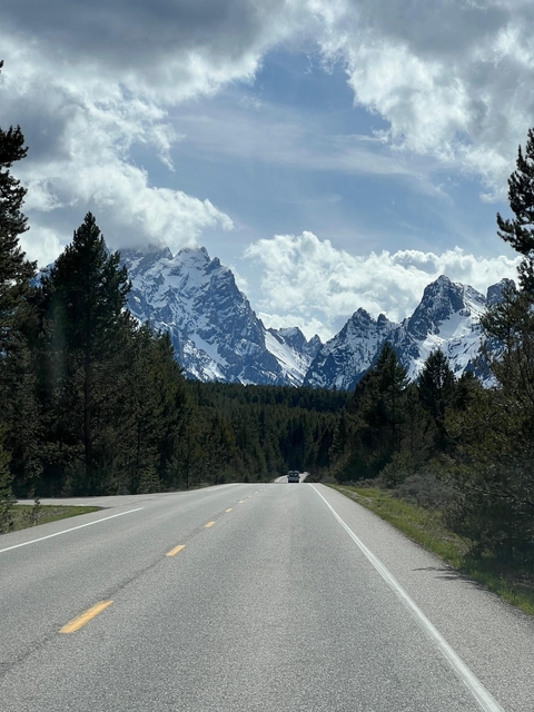       Snow-capped mountains in the background of a winding road.
  