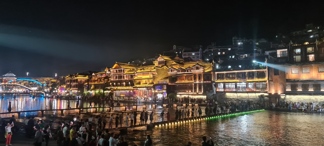 Night view of a historic water town with bright lights and people strolling.
