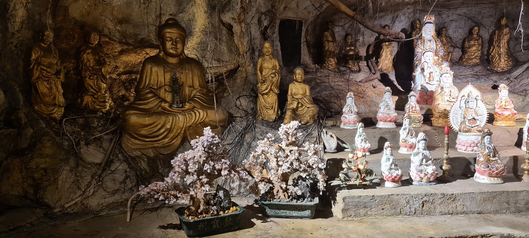       Cave with multiple statues including a large Buddha.
  