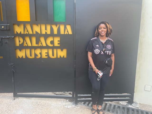       Woman standing by Manhyia Palace Museum gate.
  