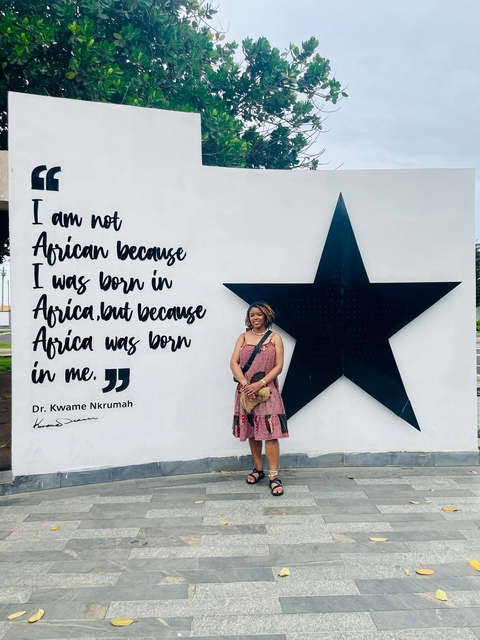       Woman standing by a wall with a famous quote.
  