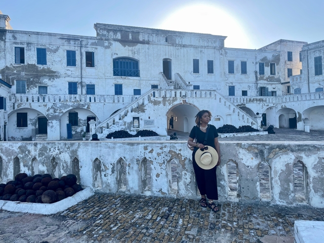       Woman in front of Cape Coast Castle.
  