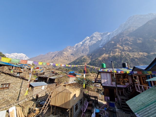       Mountain village with colorful prayer flags.
  