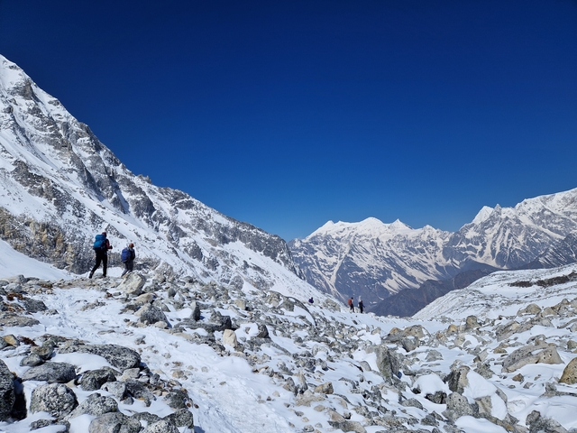       People hiking in a snowy mountainous region.
  