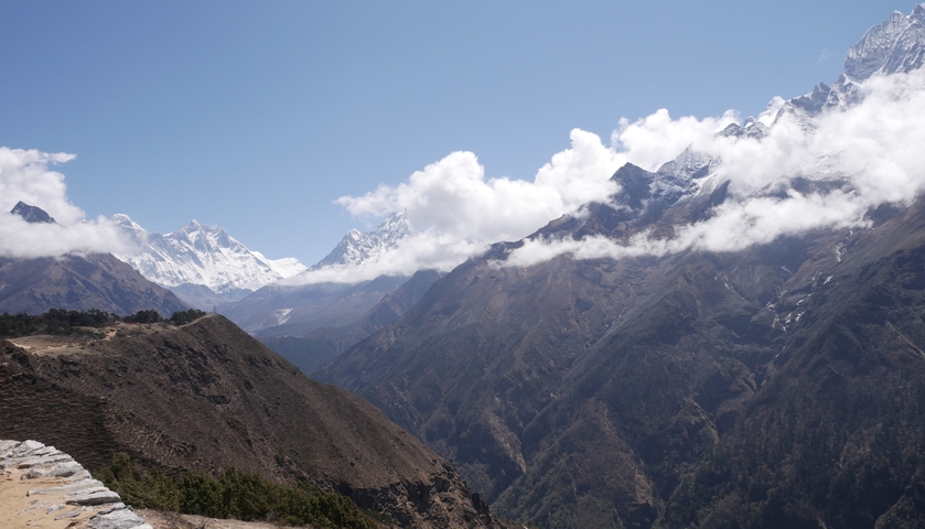 Snowy peaks and lush valleys under blue sky.