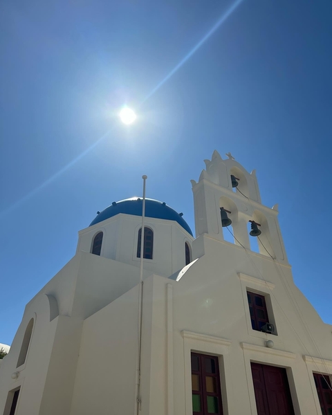 Iconic blue domed church under bright sunlight.