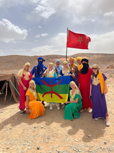       Group wearing traditional attire with a flag.
  