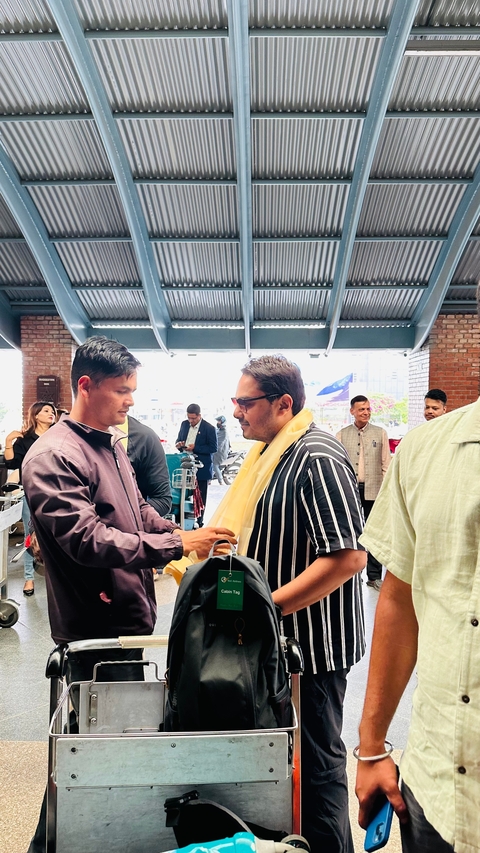 Man welcoming another with a scarf indoors.