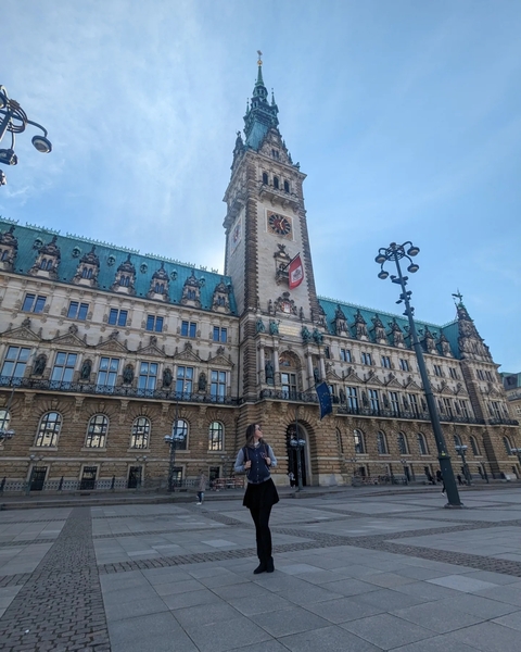 Large historic building with a clock tower and people in the foreground.
