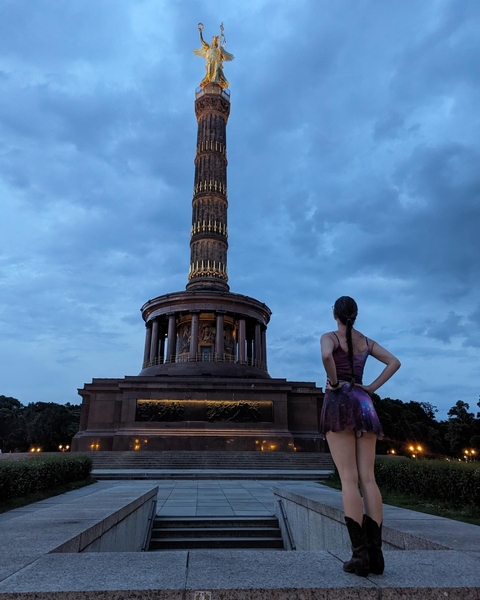 Woman looking at the Victory Column under a cloudy sky.