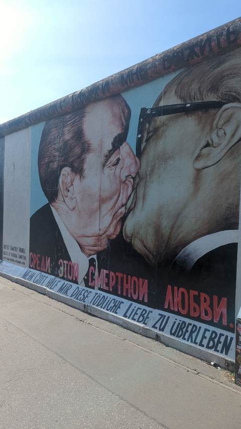 Mural of a famous kiss on a historic wall.