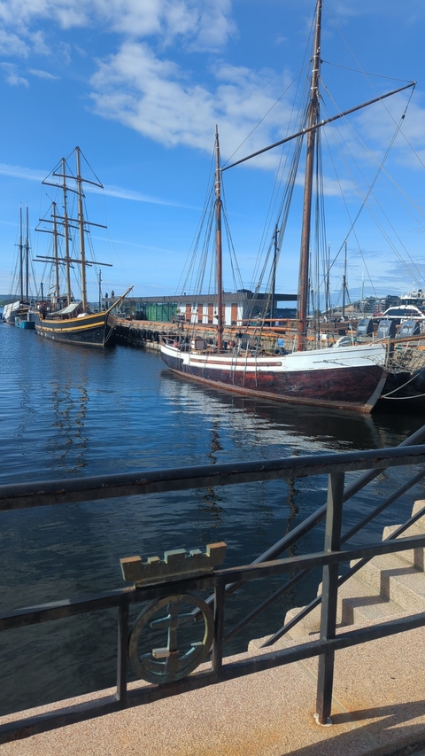 Ships docked at a harbor under a clear sky.