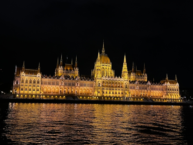       Night view of an illuminated grand building by the river.
  