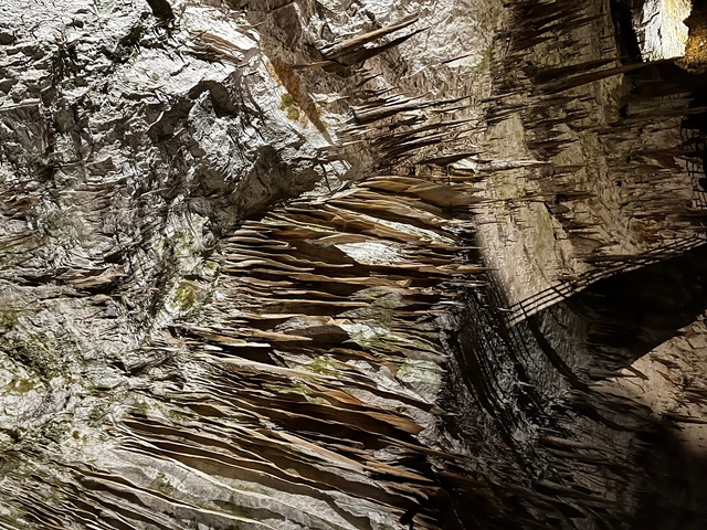       Interior view of a cave with rock formations and stalactites.
  