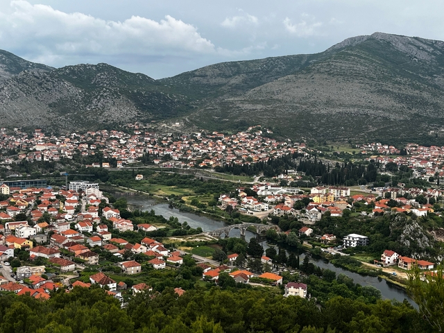       Overlooking a city with orange-tiled roofs and a river flowing through it.
  