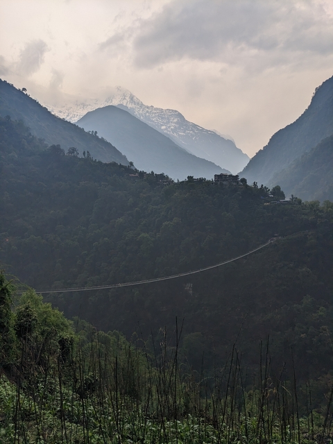       Long suspension bridge with mountains in the background.
  