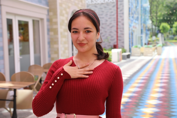 Young woman posing with hand gesture on a colorful street.