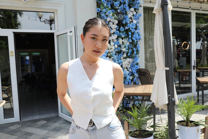 Woman in a white outfit posing in front of a decorative backdrop.