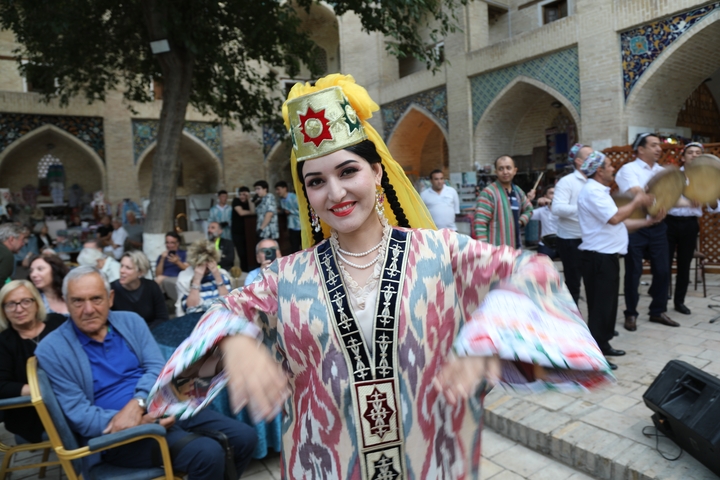 Woman in traditional dance costume amid a crowd.