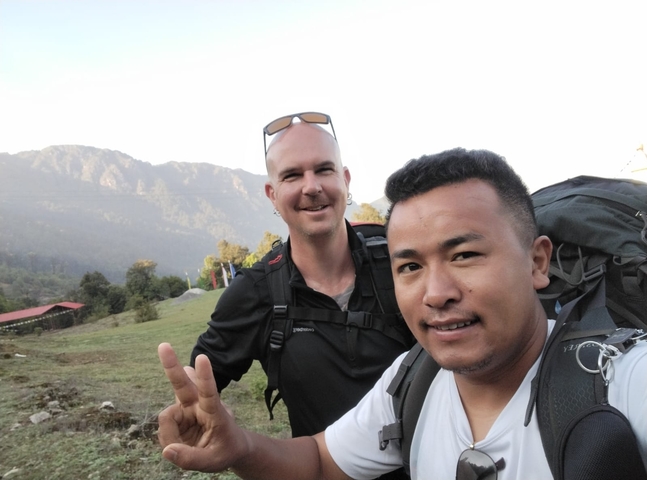       Two hikers smiling with a hilly landscape in the background.
  