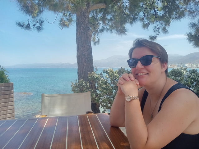       Woman sitting at an outdoor cafe near the sea.
  