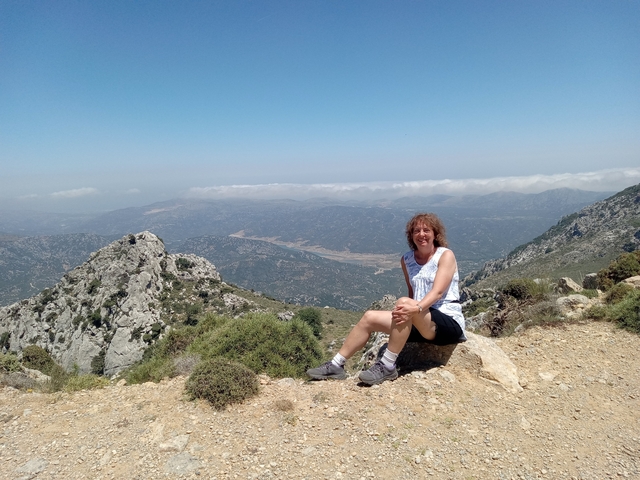       Woman sitting on a mountain path with a scenic view.
  