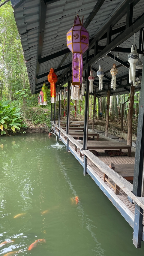       Outdoor seating area by the water surrounded by lush greenery.
  