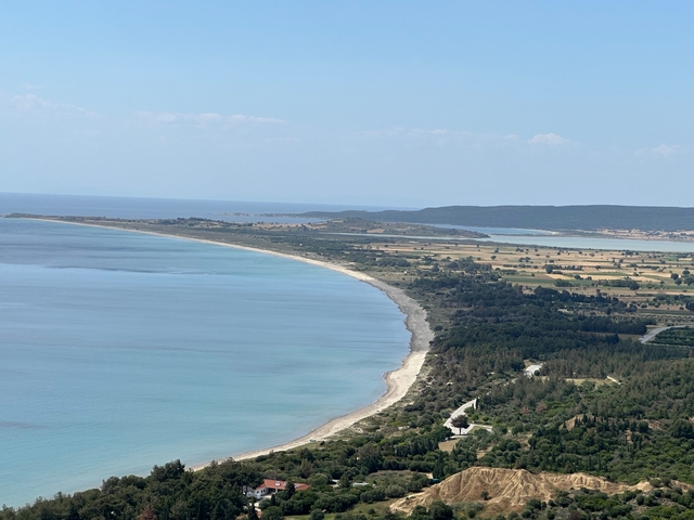       Aerial view of a coastline with the sea meeting lush fields.
  