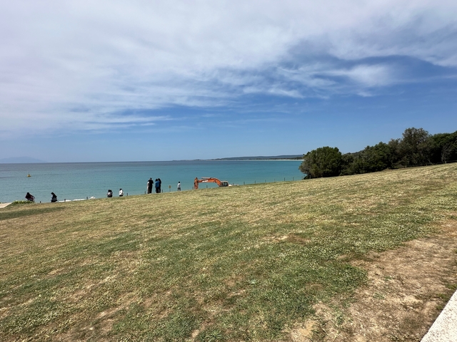       Scenic view of the sea and coastline with people in the foreground.
  
