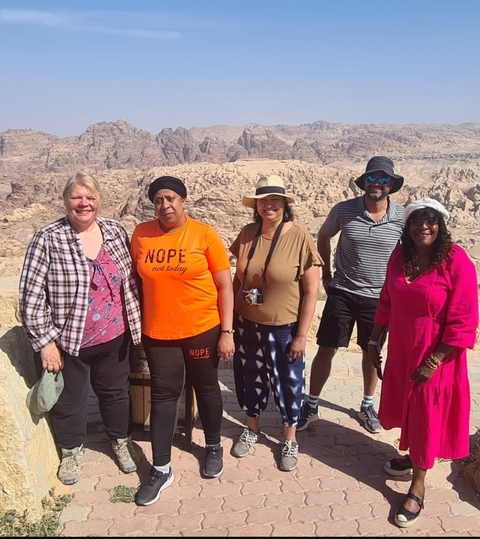       A group of people posing in front of a rocky desert landscape.
  