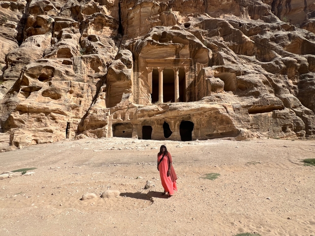       A person standing in front of ancient rock-cut architecture.
  