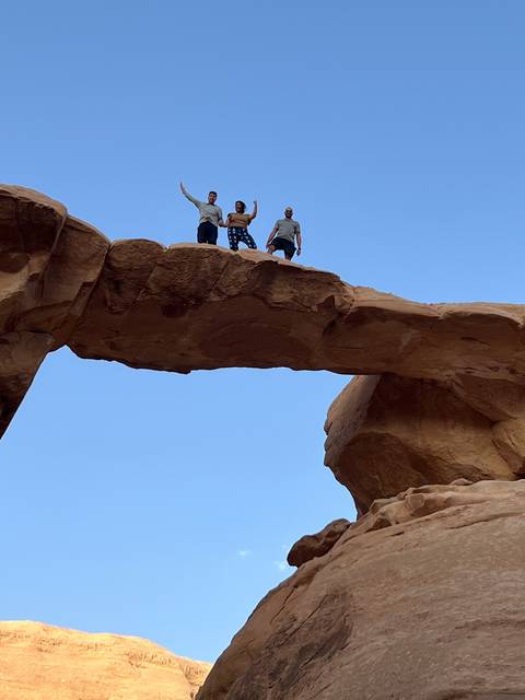       People standing on a natural rock bridge formation.
  