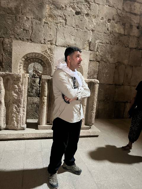       A person standing inside an ancient stone structure.
  