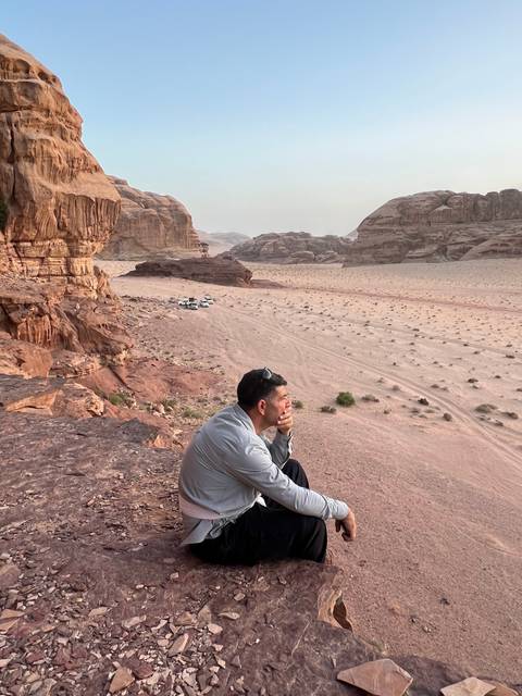       A person sitting on rocks overlooking a desert landscape.
  