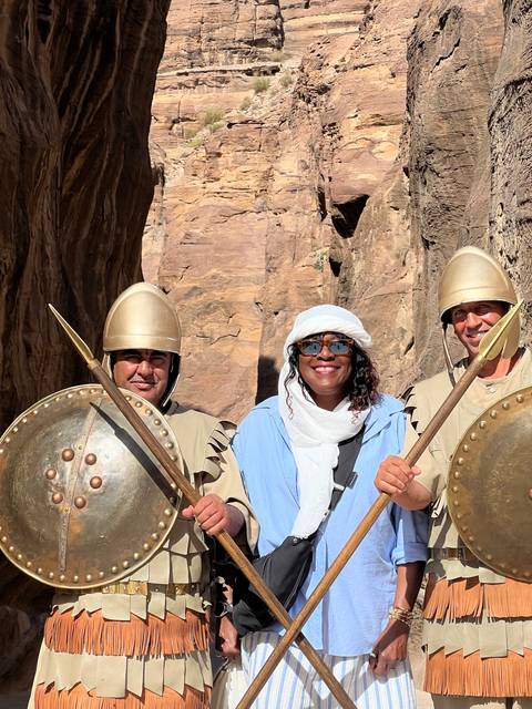       Tourist posing with local guards dressed in traditional uniforms.
  