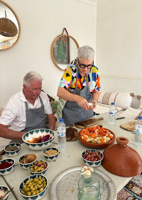 Two people preparing food in a kitchen with vibrant aprons.