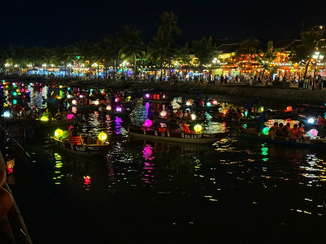 Lantern-lit boats on a river during a festival at night.