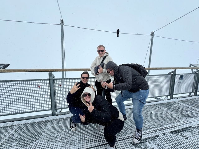 Group posing on a snowy platform with foggy background.