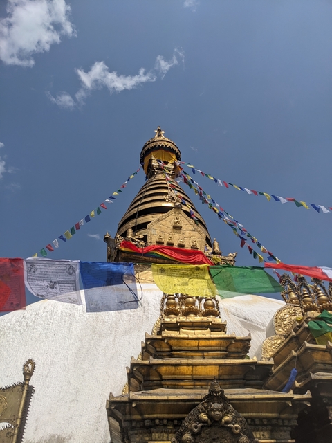 Stupa with prayer flags against a blue sky.