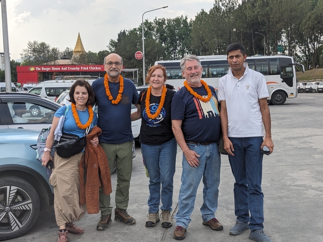       Group of tourists posing with flower garlands.
  