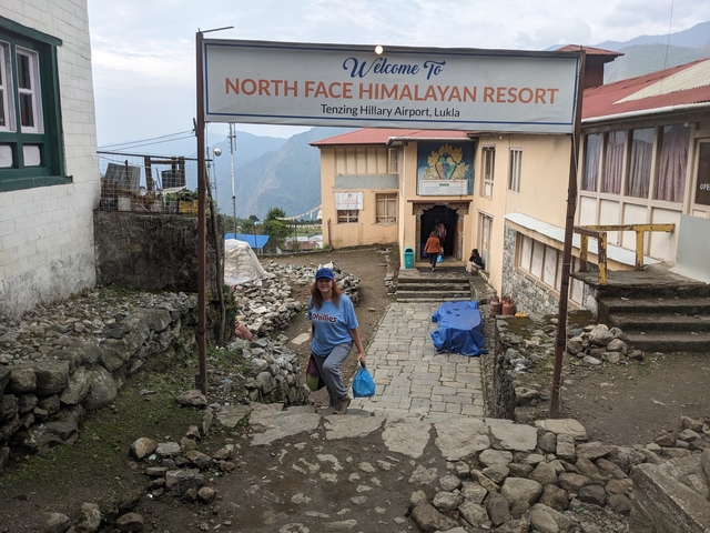 Person walking toward a resort with a sign for Tenzing Hillary Airport.