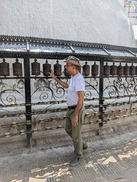       Man interacting with prayer wheels at a temple.
  