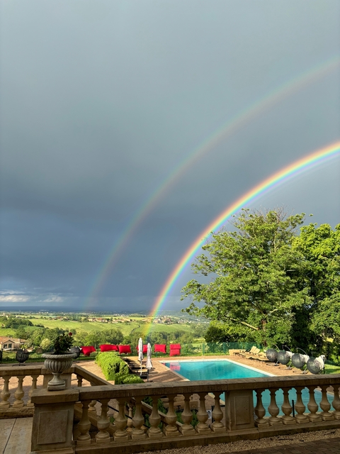 Two rainbows forming over a lush green landscape.