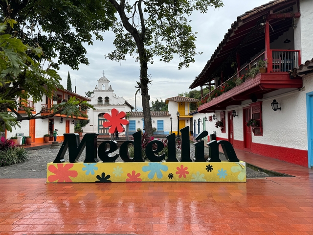       Colorful Medellín sign in a plaza with traditional buildings.
  