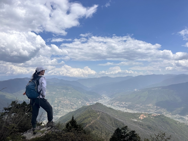 Hiker overlooking a vast mountain valley view.