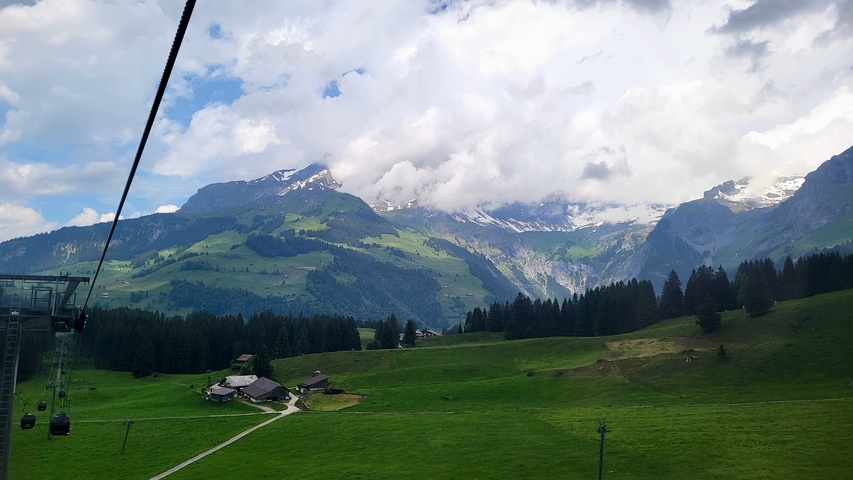 Gondola lift ascending a hillside with mountain views.