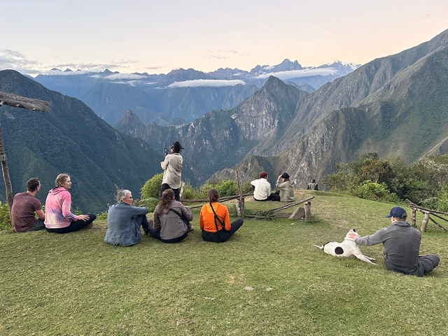       A group of people sitting on a mountain overlook enjoying the scenic views.
  