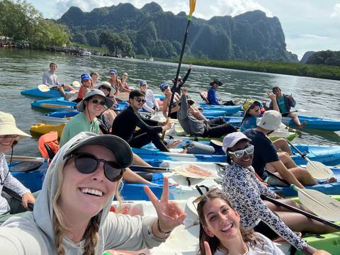 A large group of people in kayaks on a river, smiling and posing for a group photo.